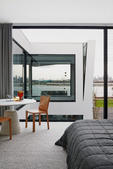 Modern and minimalist bedroom with floor-to-ceiling windows offering a scenic city view.