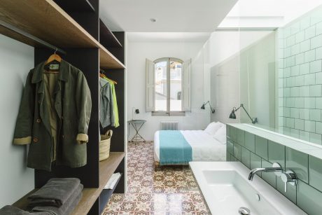 Bright and airy bedroom with patterned tile flooring, built-in closet, and bathroom.