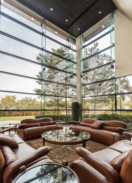 Sprawling living space with glass walls, plush leather seating, and a round glass-topped coffee table.