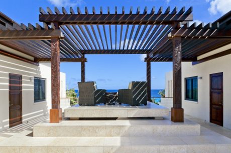 Elegant wooden pergola framing a scenic ocean view, complemented by modern furnishings.
