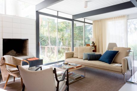 Modern living room with large windows, neutral furniture, and architectural details.