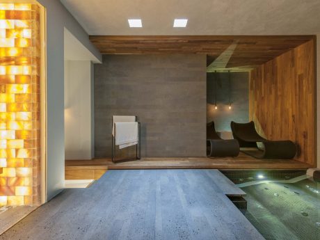 A modern spa-like interior with wooden accents, concrete walls, and a raised seating area.