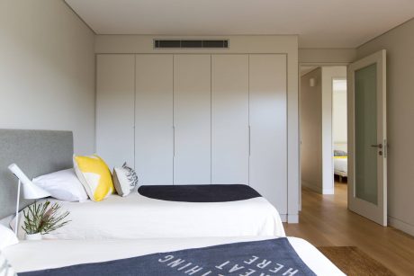 Minimalist bedroom design with built-in closets, neutral color palette, and wooden flooring.