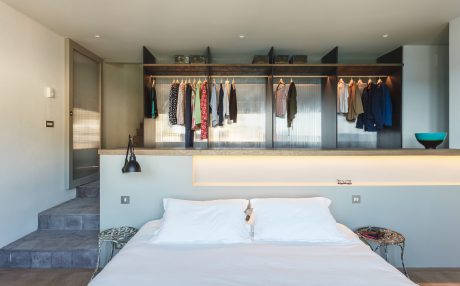 Spacious bedroom with open closet storage, recessed lighting, and minimalist decor.