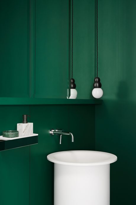 Minimal, modern bathroom in deep green with simple fixtures and minimalist design.