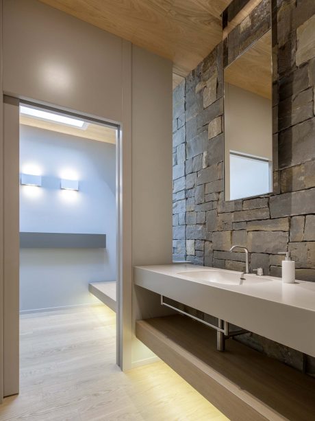 Minimalist bathroom design with stone accent wall, floating vanity, and recessed lighting.