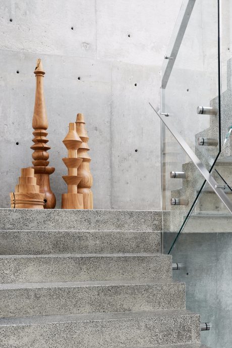 Concrete and glass staircase with abstract wooden sculptures on display.