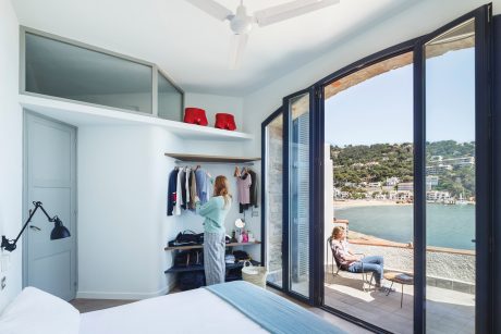 Modern bedroom with expansive glass doors offering scenic coastal view.