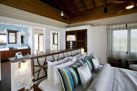 Rustic wooden ceiling beams, sleek white furnishings, and mosaic tile backsplash.
