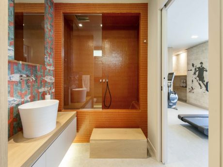 Vibrant orange tiled bathroom with sleek modern fixtures and artwork on the wall.