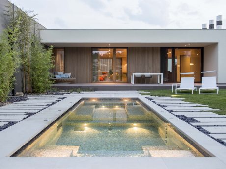 Modernist architectural design featuring a sleek rectangular structure, an illuminated pool, and a tranquil outdoor space.