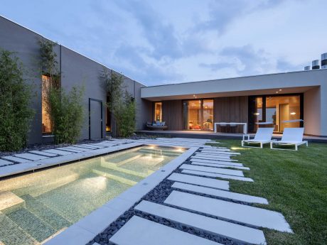 Modern architectural design with sleek lines, lush greenery, and a tranquil reflecting pool.