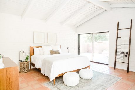 Bright, airy bedroom with vaulted ceiling, terracotta tile floor, and wooden furnishings.