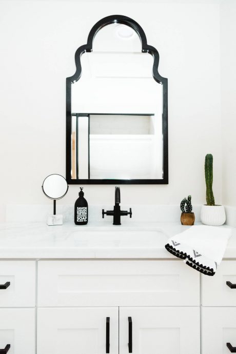 Ornate black mirror frame above a white vanity, accented with minimalist decor.