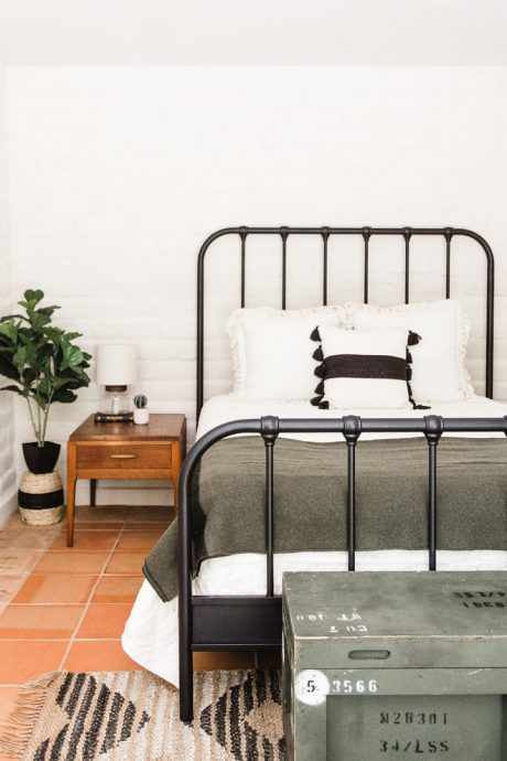 Cozy bedroom with metal bed frame, nightstand, and rustic decor accents.
