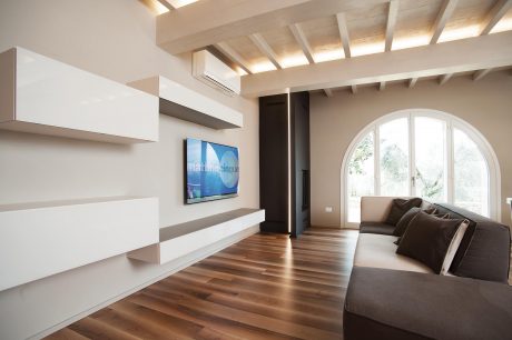 Spacious living room with beamed ceiling, arched window, and modern furniture.