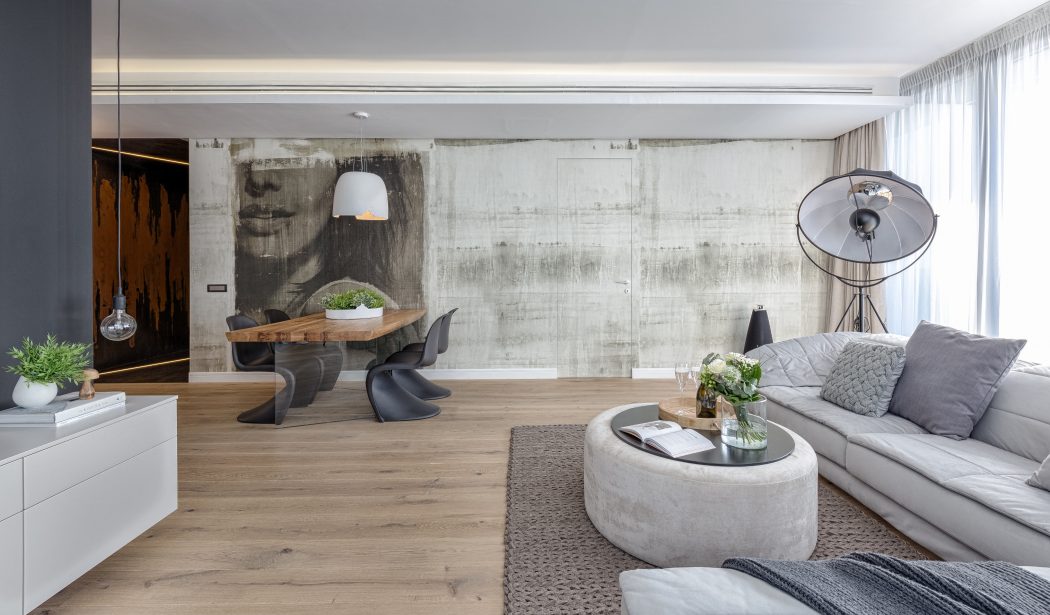 Minimalist living room with concrete walls, wood furniture, and modern lighting fixtures.