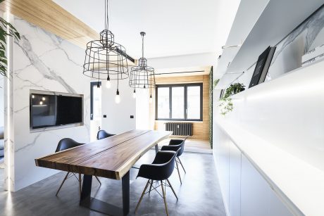 Modern dining room with sleek white cabinetry, wooden table, and sculptural pendant lights.