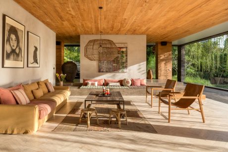 Rustic wooden ceiling, cozy seating arrangement, woven lamp, and expansive outdoor view.