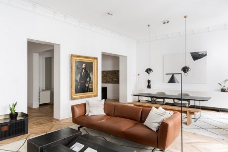 Luxurious living room with gold-framed artwork, modern furniture, and sleek lighting fixtures.