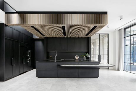 Modern kitchen with sleek black cabinetry, wood-slat ceiling, and minimalist design.
