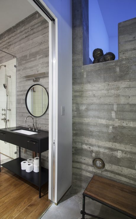Minimalist bathroom design with concrete walls, round mirror, and black vanity.