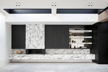 Sleek, modern kitchen with contrasting black cabinetry and white marble countertops, recessed lighting.