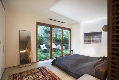 Spacious bedroom with modern decor, large window overlooking lush greenery.