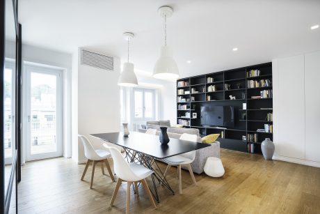 Modern and minimalist dining area with sleek black shelving, pendant lighting, and wooden floors.