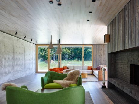 Spacious, modern living room with wooden beams, large windows, and vibrant green chairs.