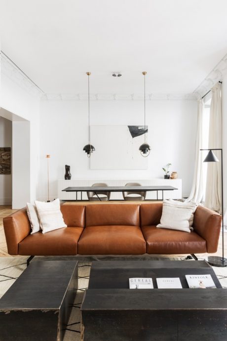 A modern living room with a leather sofa, wood furniture, and minimalist decor.