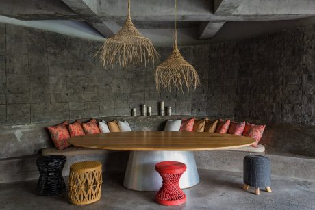 Rustic dining space with woven pendant lights, wooden table, and colorful textiles.