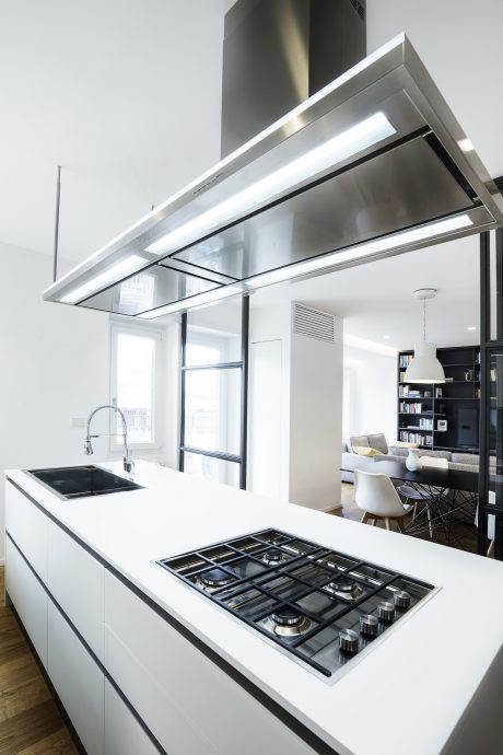 Sleek, modern kitchen with stainless steel range hood, gas cooktop, and white countertops.