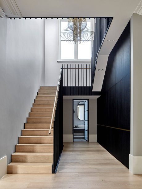 A modern, minimalist staircase with sleek black railings and an intricate light fixture.