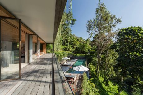 A modern wooden home with a covered patio and a lush, green landscaped garden.