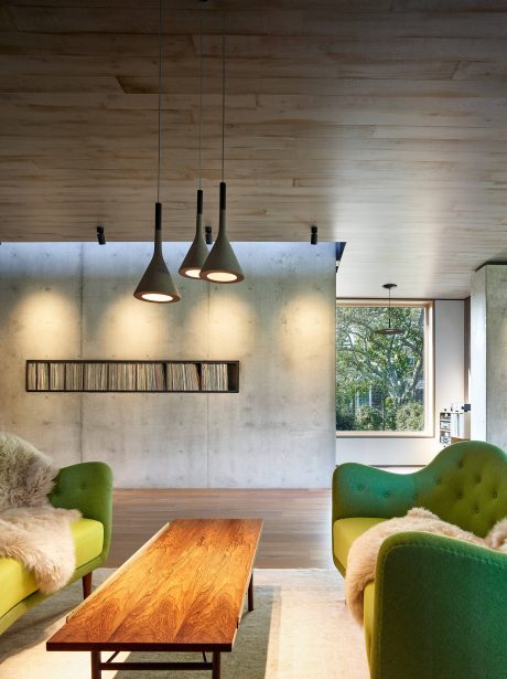 Warm, rustic interior with wooden walls, pendant lights, and plush, colorful furniture.