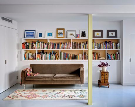 Well-organized living room with floor-to-ceiling bookshelves, a cozy sofa, and eclectic decor.