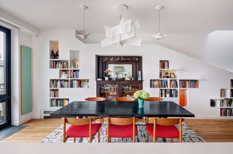 Bright, modern dining room with bookshelves, pendant lighting, and a large wooden table.