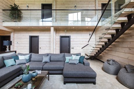 Spacious open-concept living room with wooden walls, minimalist furniture, and a modern staircase.
