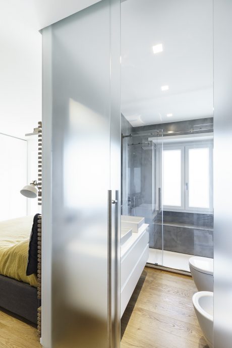 Minimalist bathroom with glass walls, built-in drawers, and wood floors.