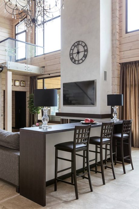 Elegant open-concept living room with a wall-mounted clock, chandelier, and wood-paneled walls.