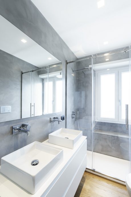 Sleek bathroom with concrete walls, glass shower, and modern vessel sinks.