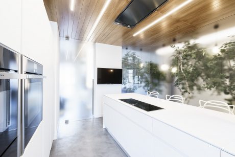 A modern, minimalist kitchen with clean lines, wooden accents, and a sleek white countertop.