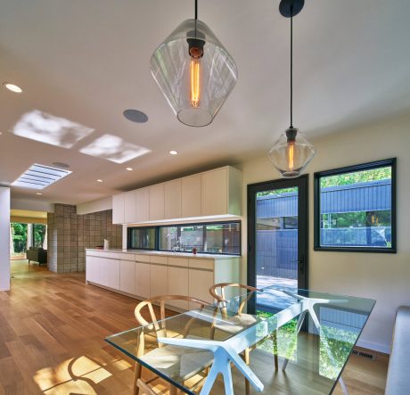 A modern kitchen with glass pendant lights, wood floors, and sleek cabinetry.