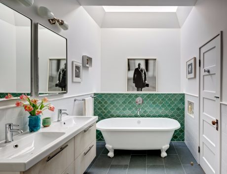 Elegant bathroom featuring a clawfoot tub, tiled walls, and framed artwork.