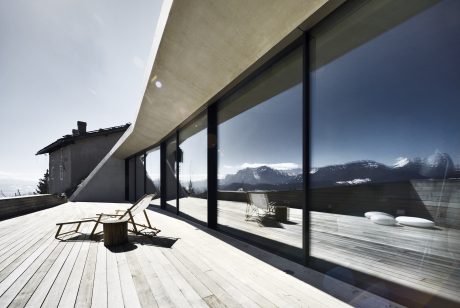 Expansive glass facade overlooking a snowy mountain landscape, featuring minimalist decor.