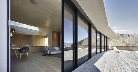 A modern architectural masterpiece with sleek, floor-to-ceiling windows offering stunning mountain views.
