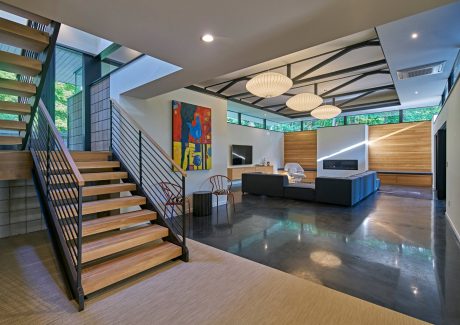 Spacious modern interior with wooden staircase, pendant lights, and exposed ceiling beams.