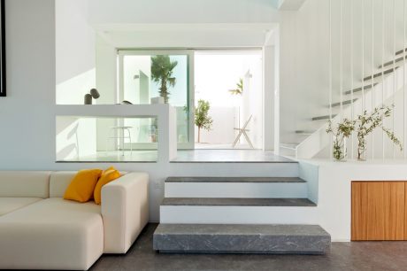 Bright, minimalist living space with sleek stone steps and open doorway framing outdoor scene.