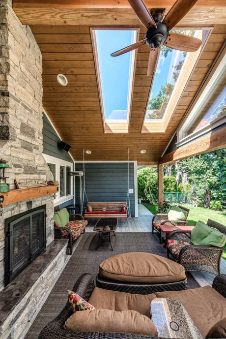 Cozy covered patio with exposed wooden beams, stone fireplace, and plush seating.